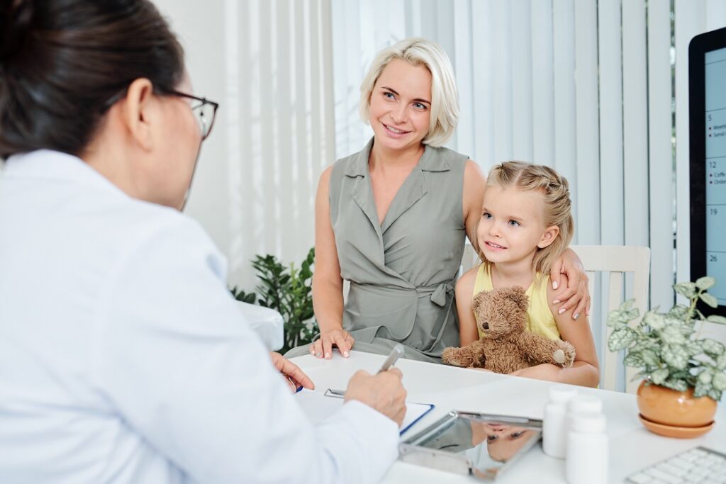 Smiling woman and her little daughter listening to recommendations of pediatrician
